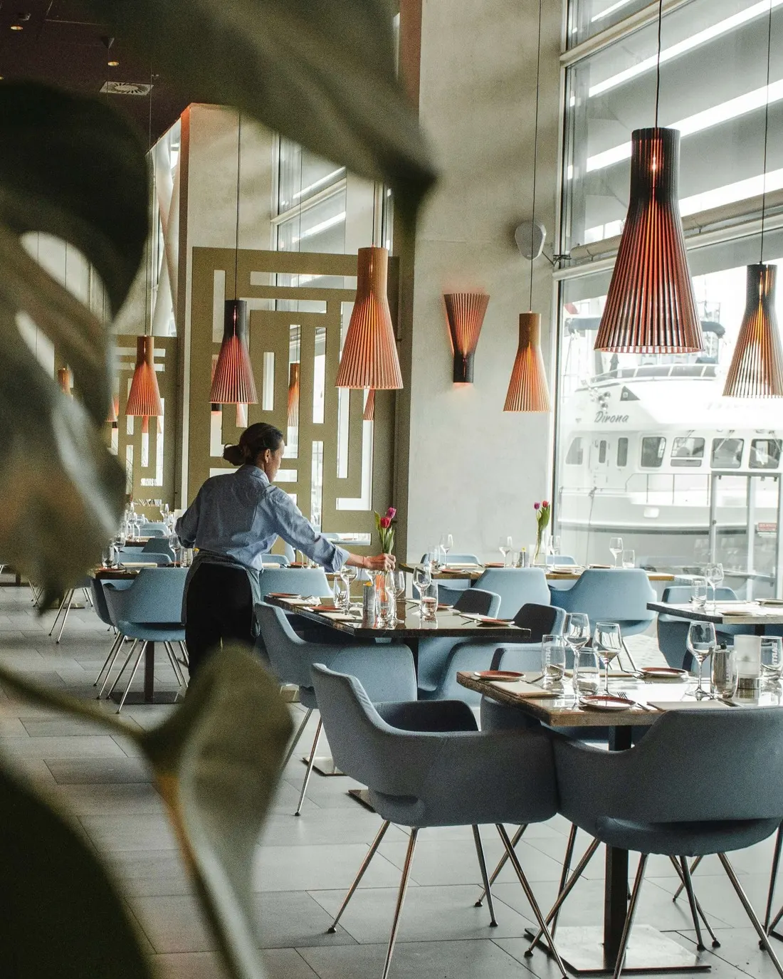 Medewerker dekt de tafels in een restaurantzaal, vlak voor de eerste gasten binnenkomen