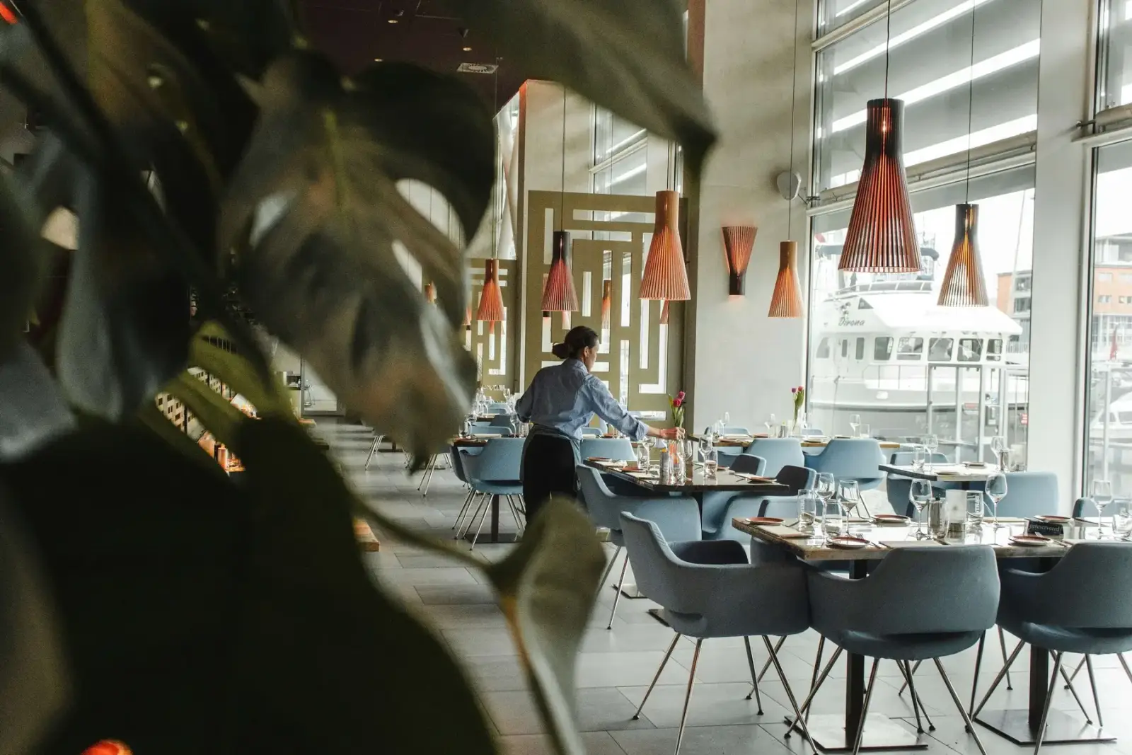 Medewerker dekt de tafels in een restaurantzaal, vlak voor de eerste gasten binnenkomen